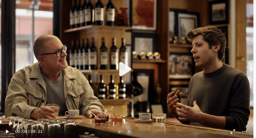 Two people converse at a bar, surrounded by bottles and framed photographs, with drinks on the counter. The setting is cozy and inviting.